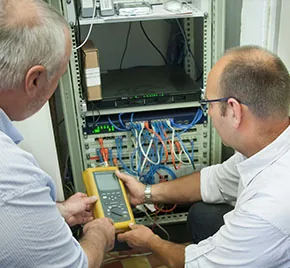Zwei Elektriker prüfen gemeinsam einen Netzwerkschrank