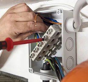 Elektriker schließt Leitungen in einer Verteilerdose an